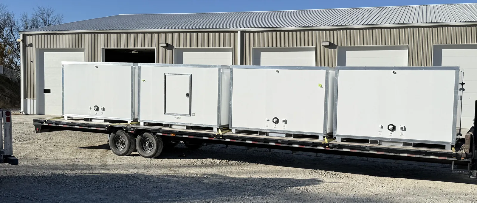 Four water and waste boxes strapped to a flatbed trailer for delivery